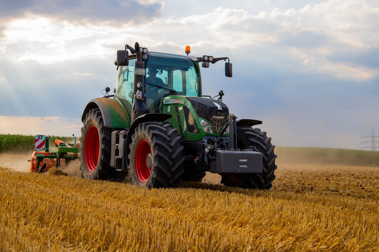 heros-img A powerful green tractor plowing a dusty wheat field under a cloudy summer sky in rural Germany.